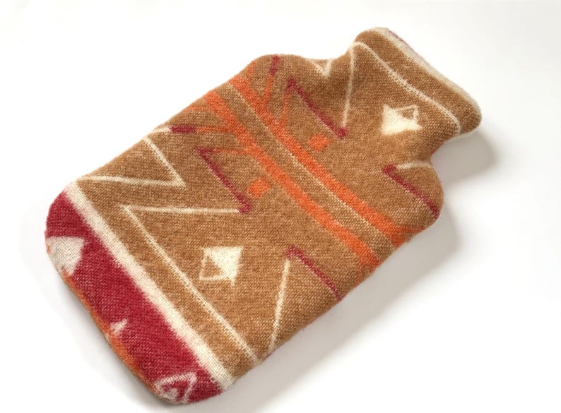 Brown geometric wool hot water bottle cover with angled zigzag lines and burgundy corner detail on white background