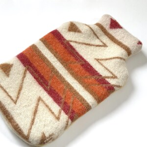 Cream wool hot water bottle cover with zigzag pattern and rust/burgundy stripes on a white background