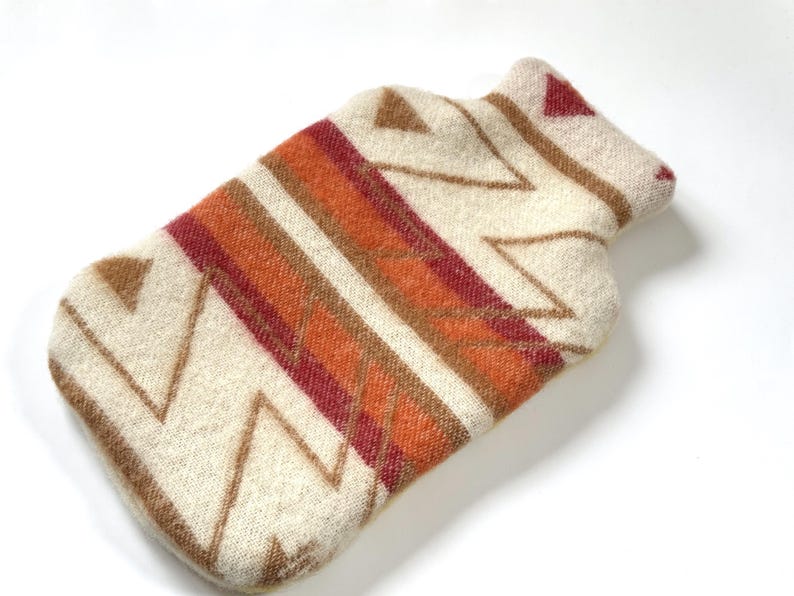 Cream wool hot water bottle cover with zigzag pattern and rust/burgundy stripes on a white background