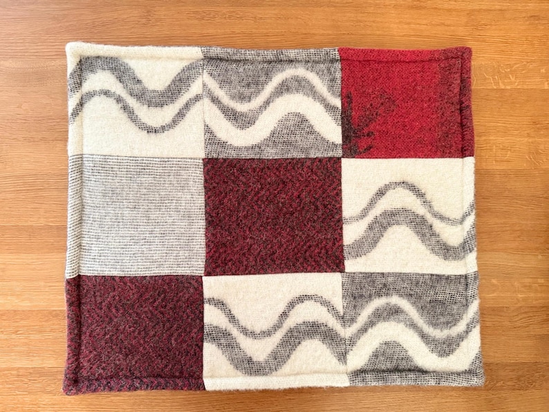 Side profile view of the hem of the wool pet mat, showing the thickness and finished edge.