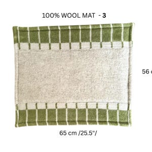 K&ouml;nnte beinhalten: Rechteckige Wollmatte, 56 cm x 65 cm, mit einem beigen Mittelteil und gr&uuml;n-wei&szlig; karierten R&auml;ndern. Der Text "100% WOOL MAT - 3" befindet sich oben.