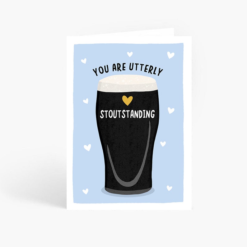 May include: A blue card with a white border and white hearts. The card features a black and white illustration of a glass of stout beer with a gold heart on the side. The text "You are utterly stoutstanding" is written in black on the card.