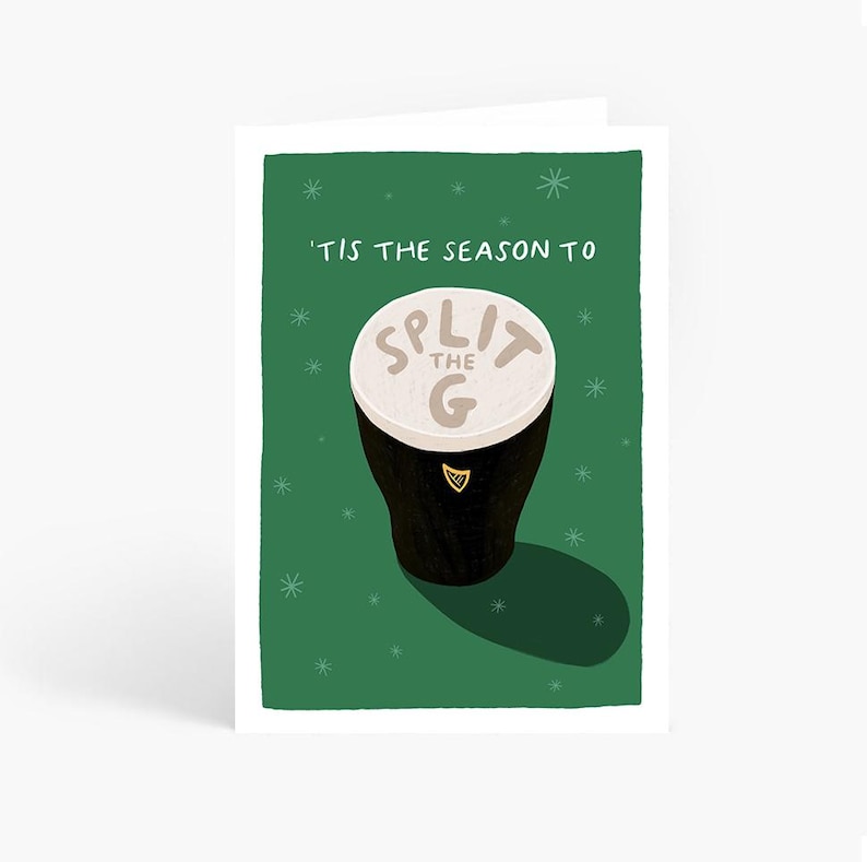 May include: Greeting card with a green background and white snowflakes. The card features a cartoon illustration of a pint of stout with the text "'TIS THE SEASON TO SPLIT THE G". The pint has a white foamy top.