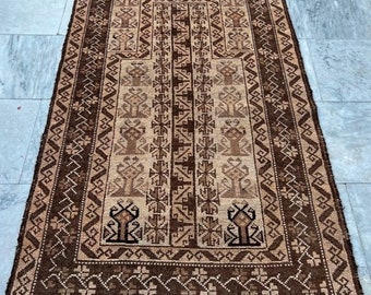 Puede incluir: Una alfombra de oración tradicional marrón y beige con intrincados patrones geométricos. La alfombra tiene un borde con flecos y un diseño central que se asemeja a una mezquita.