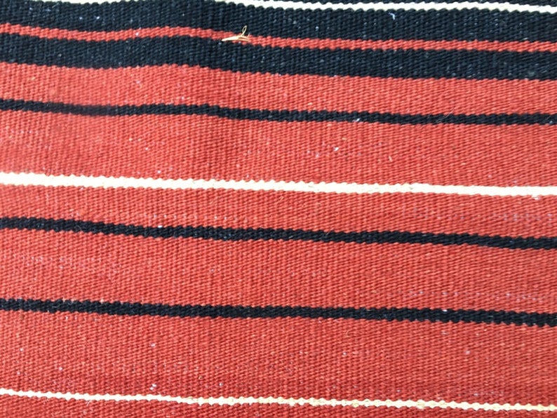 Pu&ograve; includere: Tessuto rosso con strisce bianche e nere. Il tessuto ha una trama tessuta.
