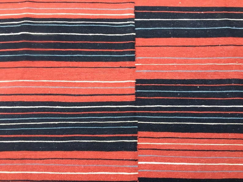 Pu&ograve; includere: Tessuto tessuto a righe rosse, nere e bianche. Il tessuto presenta un motivo orizzontale con righe alternate di rosso, nero e bianco.