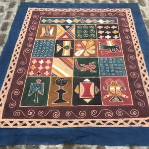 Könnte beinhalten: Ein farbenfroher Patchwork-Deckenbezug mit blauem Rand. Der Bezug besteht aus Quadraten mit verschiedenen Mustern und Designs, darunter geometrische Formen, Vögel und menschliche Figuren. Der Bezug ist aus einem weichen, natürlichen Stoff gefertigt.