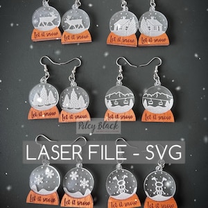 Könnte beinhalten: Acht Paar lasergeschnittene Holzohrringe mit transparenten Acryl-Schneekugeln. Jede Schneekugel zeigt eine andere Winterszene und die Worte "Let it snow" auf der Basis.