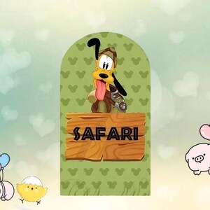 以下が含まれることがあります： サファリ衣装のプルートの漫画イラスト。ピンクの舌が出ている。背景はミッキーマウスの頭の形をした緑色。木製の看板には「SAFARI」と書かれています。