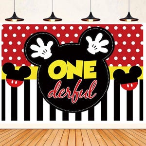 May include: A black and yellow Mickey Mouse head backdrop with red polka dots and black and white stripes. The backdrop says "ONE derful" in yellow and red letters.