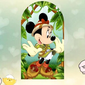 Puede incluir: Imagen de dibujos animados de Minnie Mouse con atuendo de safari, que incluye un sombrero caqui con un lazo rojo, una chaqueta verde y botas marrones. Est&aacute; rodeada de follaje y enredaderas verdes, con un fondo verde claro.