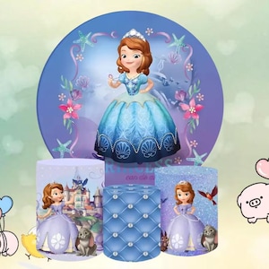 May include: A princess-themed party decoration set featuring a cartoon princess in a blue and purple dress. The set includes a large circular backdrop and three cylindrical stands with princess imagery and a quilted design.