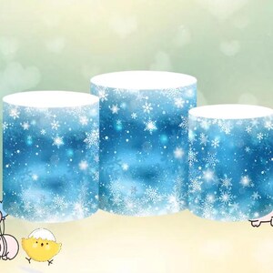 May include: Three round cake stands with a blue and white snowflake pattern. The stands are different sizes and are stacked on top of each other.