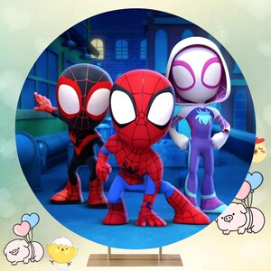 Puede incluir: Un tel&oacute;n de fondo redondo con tres personajes de Spider-Man de dibujos animados: Spider-Man, Miles Morales y Spider-Gwen. Los personajes est&aacute;n en una postura de acci&oacute;n din&aacute;mica sobre un fondo azul con un horizonte de ciudad en el fondo.