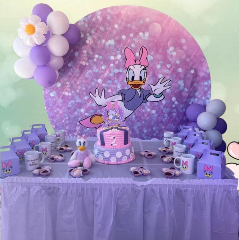 May include: A purple and white birthday party table setting with a two-tiered cake decorated with a cartoon duck, a purple and white backdrop with a cartoon duck, and purple and white party favours.