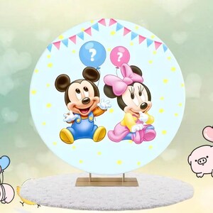 May include: A circular, light blue decorative item with Mickey and Minnie Mouse illustrations. Mickey is in blue dungarees, Minnie in a pink bow and dress. They hold question mark balloons. The background has yellow stars and a banner.