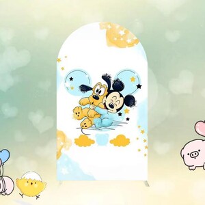 May include: A white arch-shaped backdrop featuring a cartoon illustration of Mickey Mouse and Pluto hugging. The design includes blue and yellow accents with stars and clouds. The backdrop is suitable for a party or event.