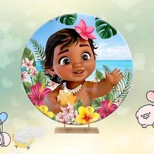 May include: A round backdrop featuring a cartoon illustration of a smiling baby girl with dark skin, wearing a flower in her hair and a shell necklace. The backdrop includes tropical flowers, green leaves, and a blue ocean scene.