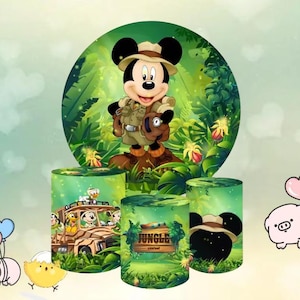 May include: A vibrant jungle-themed party decoration set featuring Mickey Mouse in safari attire. The set includes a large circular backdrop and cylindrical containers with jungle and character graphics. The backdrop showcases Mickey in a jungle setting.