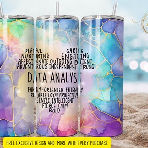 May include: A stainless steel tumbler with a colorful abstract design and gold accents. The tumbler features text that reads "Playful, Nurturing, Affectionate, Outgoing, Patient, Adventurous, Independent, Strong, Data Analyst, Family-Oriented, Friendly, Reliable, Loyal, Protective, Gentle, Intelligent, Fierce, Calm, Bold".