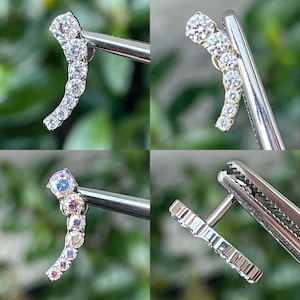 May include: A selection of curved ear piercing jewellery. The jewellery features a series of clear, round gemstones set in a curved line. The metal is silver or gold in colour. The gemstones are clear and iridescent.