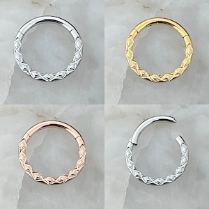 May include: Four different colored seamless rings with a diamond pattern. The rings are silver, gold, rose gold, and a lighter silver. The rings are all the same size and shape.