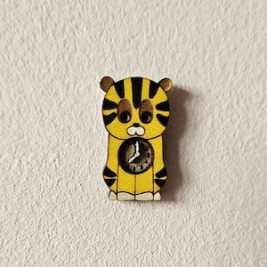 Könnte beinhalten: Eine gelbe und schwarze Holztigeruhr mit schwarzem Zifferblatt und weißen Zeigern.