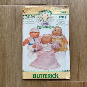 May include: A vintage Cabbage Patch Kids sewing pattern with instructions for making clothes for the dolls. The pattern is for sizes Preemie Nouveau-Ne. The pattern number is 6980. The pattern is from the company Butterick.