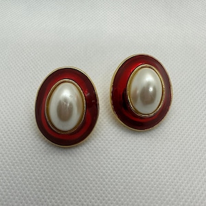 May include: A pair of red and gold oval earrings with a white pearl center.
