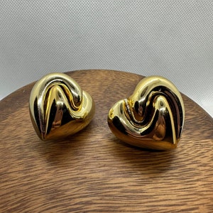 May include: A pair of gold-tone heart-shaped earrings with a twisted design.