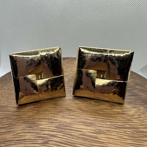 May include: A pair of gold-toned square earrings with a hammered texture and a woven design.