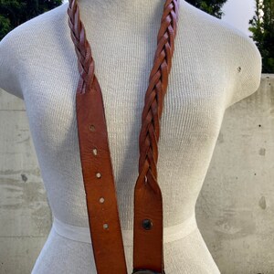 May include: A brown leather braided belt with a silver fish buckle.