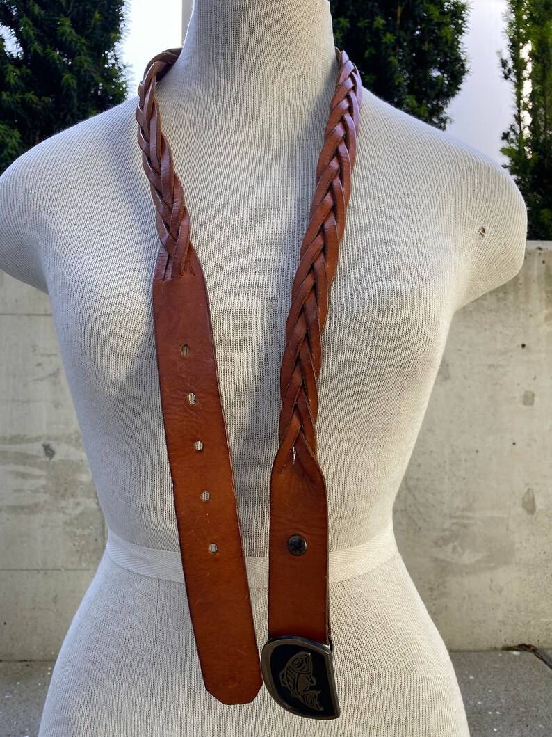May include: A brown leather braided belt with a silver fish buckle.