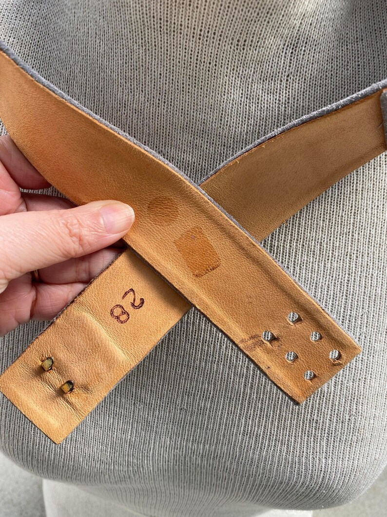 May include: A brown leather belt with a buckle and a size 28 stamped on the back.
