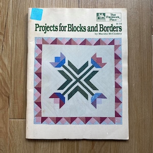 May include: A book titled "Projects for Blocks and Borders" by Marsha McCloskey. The book cover features a colourful quilt block design with a green, pink and blue colour scheme.