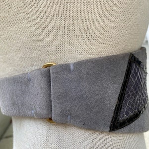 May include: A gray suede belt with a gold buckle and a black snakeskin detail.