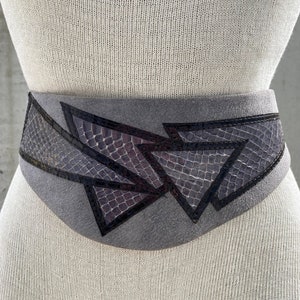 May include: A gray suede belt with a geometric design featuring black and purple snakeskin accents.