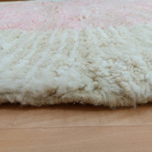 May include: Close-up of a fluffy, white and pink rug with a soft, textured surface.