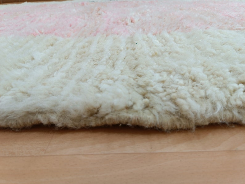 May include: Close-up of a fluffy, white and pink rug with a soft, textured surface.