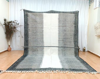 May include: A black and white striped rug with a white centre stripe. The rug has a fringe border and is made of wool.