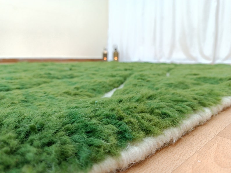 May include: A green shag rug with a white border. The rug is made of soft, fluffy fibers and has a unique, textured surface.