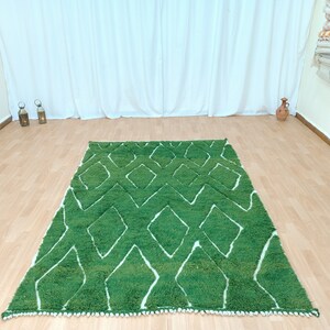 May include: A green and white patterned rug with a diamond design. The rug has a white fringe border.