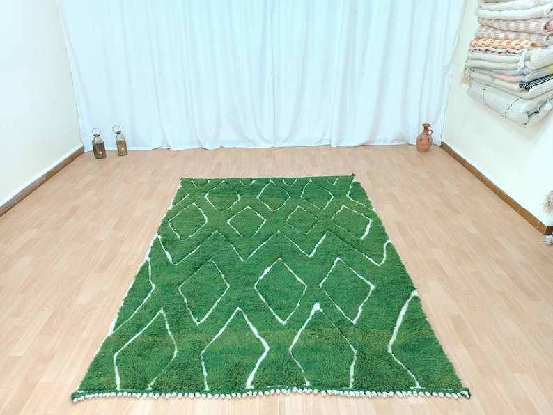 May include: A green and white patterned rug with a diamond design. The rug has a white fringe border.