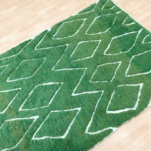 May include: Green and white rug with a diamond pattern. The rug is made of a soft, fluffy material.