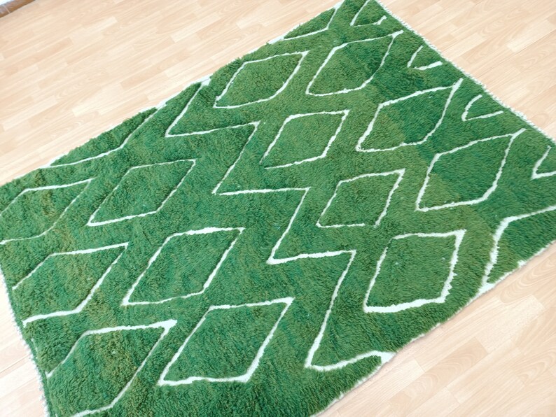 May include: Green and white rug with a diamond pattern. The rug is made of a soft, fluffy material.