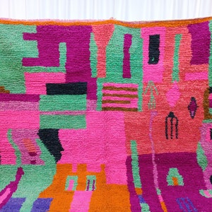 K&ouml;nnte beinhalten: Ein farbenfroher, abstrakter Teppich mit geometrischen Formen in den Farben Pink, Gr&uuml;n, Orange, Lila und Schwarz. Der Teppich ist aus einem dicken, strukturierten Material gefertigt und hat ein handgewebtes Aussehen.