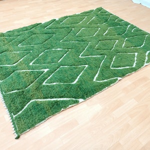 May include: Green and white area rug with a diamond pattern. The rug has a fluffy texture.