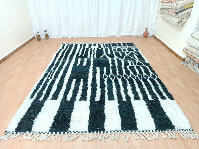 May include: Black and white striped rug with a geometric pattern. The rug has a fringed border.