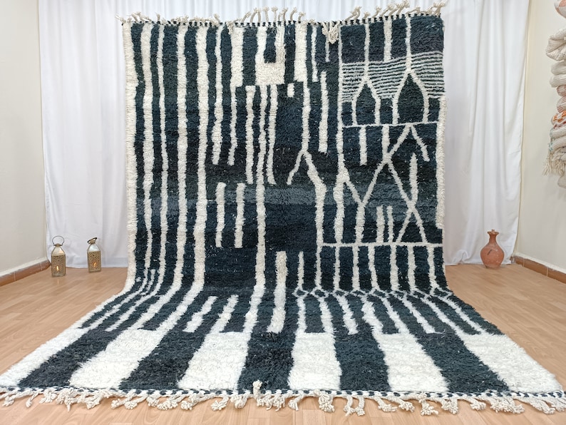 May include: A black and white geometric patterned rug with a fringe border. The rug has a modern design with abstract shapes and lines.