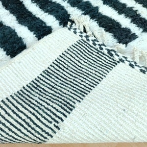 May include: Close-up of the back of a black and white striped rug with a black and white woven border. The rug is made of a soft, fluffy material.